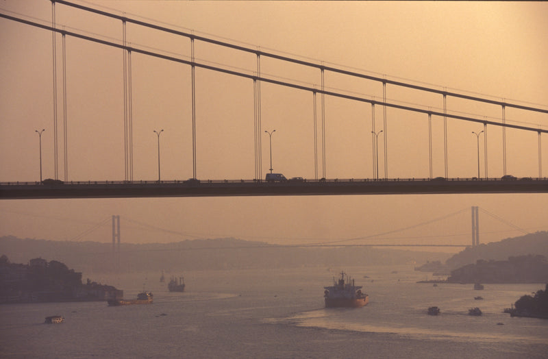 Bosphorus Bridge spanning two continents at dusk with cargo ships navigating the strait below and a second bridge dissolving into the amber mist, Istanbul fine art print