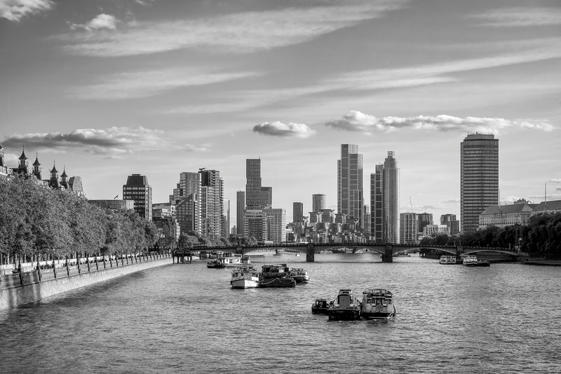 Black and white view along the Thames toward Vauxhall Bridge with Nine Elms and St George Wharf towers rising behind, houseboats moored in the foreground and Victoria Embankment trees lining the left bank, London fine art print
