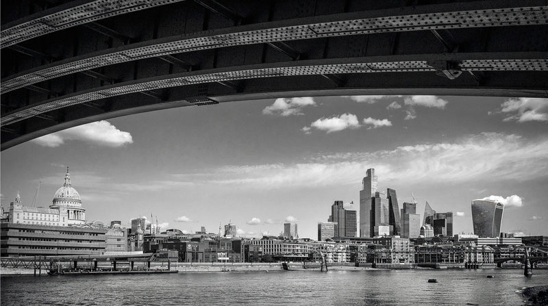 View through the steel arches of Blackfriars Railway Bridge framing St Paul's Cathedral dome and the City of London skyline with the Thames below, black and white fine art photography print